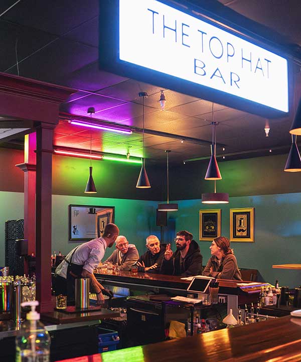 Inside The Top Hat Bar four people in background being entertained by bartender